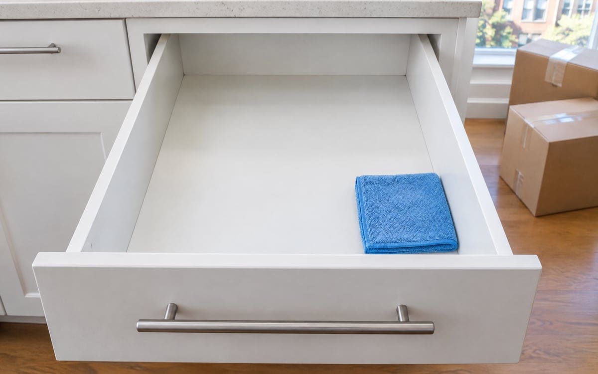 A move-in cleaning cloth folded in an empty kitchen drawer before the dishes go in.