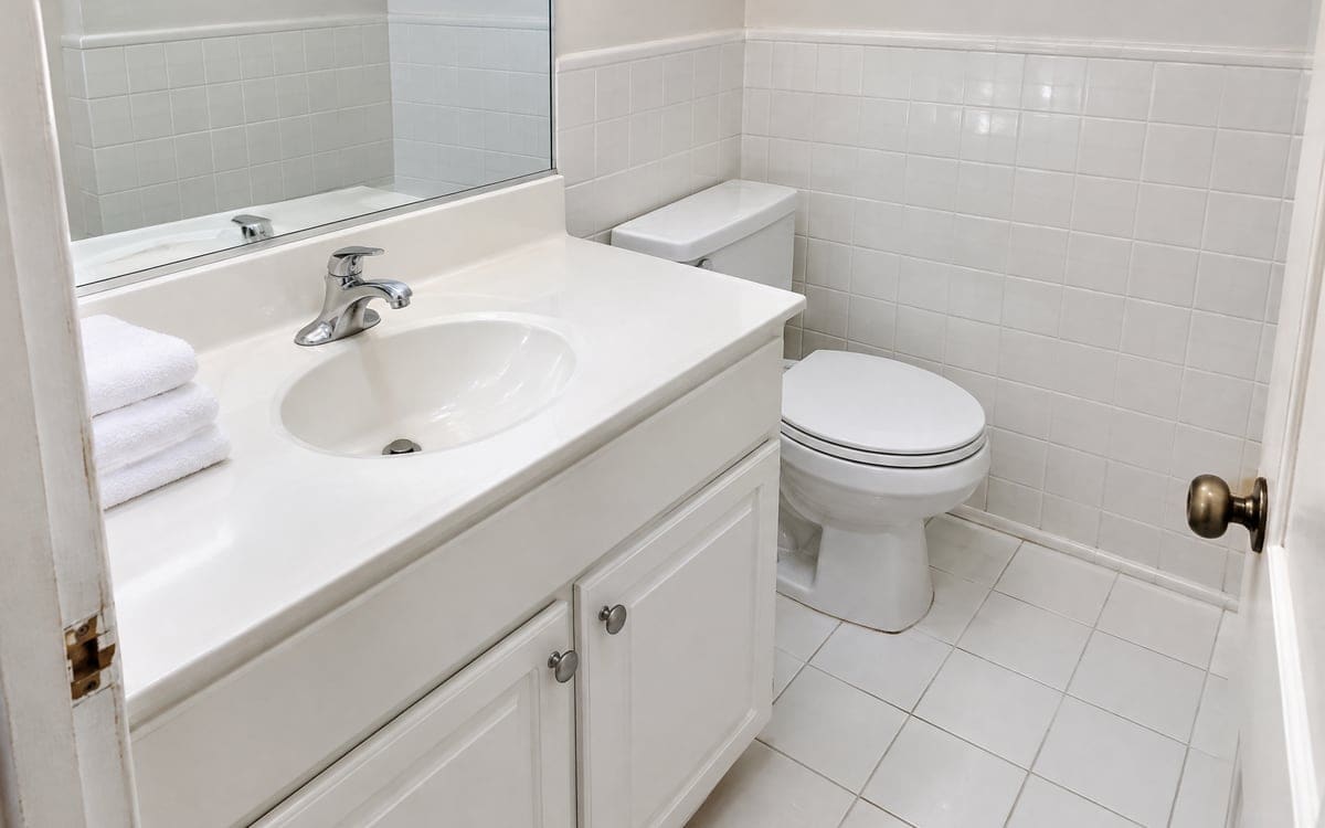 A guest bathroom cleaned on a one-time cleaning service, with a wiped vanity and folded white towels on the counter.